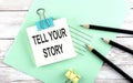 Text TELL YOUR STORY on the short note with pencils on the wooden background Royalty Free Stock Photo