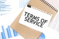 Text TERMS OF SERVICE on white paper sheet and brown paper notepad on the table with diagram. Business concept Royalty Free Stock Photo