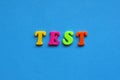 text test from plastic colored letters on blue paper background.