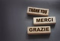 Text Thank you Merci Grazie on wooden blocks on black background. Gratitude expressed in English fFrench and Italian state of mind Royalty Free Stock Photo