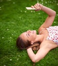 Text Thinking of you...a young woman using her cellphone while lying on the grass. Royalty Free Stock Photo