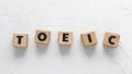 Text TOEIC on wooden cubes on white textured background. Abbreviation of `Test of English for International Communication