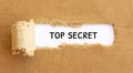Text Top Secret appearing behind torn brown paper
