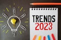 Text TRENDS 2023 on white paper between white and brown spiral notepads.