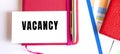 Text VACANCY on white card lying on notepad on office desk. Financial concept
