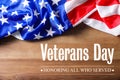 Text VETERANS DAY and USA flag on wooden background, top view