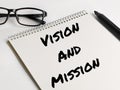 Text VISION AND MISSION on notebook with marker pen and eye glasses.