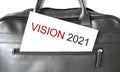 Text vision 2021 writing on white paper sheet in the black business bag. Business concept