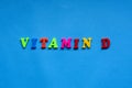 text vitamin d from plastic colored letters on blue paper background.