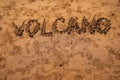 Text VOLCANO on volcanic sand. Texture, wave pattern of ocean sand on the beach. Texture of beach sand. Volcanic beach Royalty Free Stock Photo