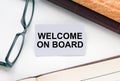 Text Welcome On Board on a business card lying next to notepad with eyeglasses and text documents Royalty Free Stock Photo