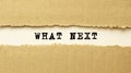 Text WHAT NEXT appearing behind torn brown paper. Top view Royalty Free Stock Photo