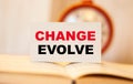 Text on white paper Change Evolve, on open book