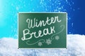 Text Winter Break and snowflakes on school chalkboard against snowdrift Royalty Free Stock Photo
