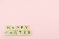 Text wooden blocks spelling the word happy easter on pink background Royalty Free Stock Photo