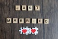 Text wooden blocks spelling the word JUST MARRIED and puzzle jigsaw red heart on brown wooden, romantic background for celebrating Royalty Free Stock Photo