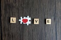 Text wooden blocks spelling the word LOVE and puzzle forming red heart on rustic brown wooden surface, romantic background for Royalty Free Stock Photo