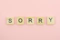 Text wooden blocks spelling the word sorry on pink background Royalty Free Stock Photo