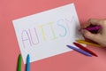 Text word autism on paper sheet written by colorful letter, on blue background.