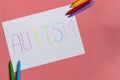 Text word autism on paper sheet written by colorful letter, on blue background.