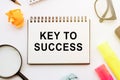 The text, the word Key To Success, is written in a notebook lying on white table with a pen, glasses and magnifier. Business Royalty Free Stock Photo