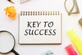 The text, the word Key To Success, is written in a notebook lying on white table with a pen, glasses and magnifier. Business Royalty Free Stock Photo