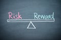 Text word risk and reward balance on seesaw drawing writing on chalkboard or blackboard background. Concept of risk and reward Royalty Free Stock Photo