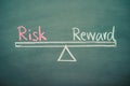 Text word risk and reward balance on seesaw drawing writing on chalkboard or blackboard background. Concept of risk and reward Royalty Free Stock Photo