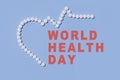 Text World Health Day. Group of white round pills forms heart figure next to heart rhythms from white pills on a blue Royalty Free Stock Photo
