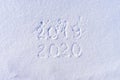 Text 2019 and 2020 written by hand on white fresh snow in sunny winter day. 2019 and 2020 years changing, new year holiday concept Royalty Free Stock Photo