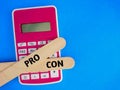 Text written Pro and Con at ice cream stick on calculator  blue background Royalty Free Stock Photo