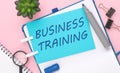 text 'BUSINESS TRAINING' on blue paper composition with stationery on color pink background. top view Royalty Free Stock Photo