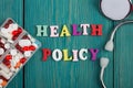 Text & x22;Health policy& x22; of colored wooden letters, stethoscope and pills