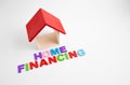 Text "HOME FINANCING" on wooden block and house model, Property home financing, family house, concept.