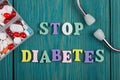 Text & x22;STOP Diabetes& x22; of colored wooden letters, stethoscope and pills