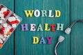 Text & x22;World Health Day& x22; of colored wooden letters, stethoscope and pills