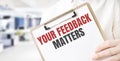 Text YOUR FEEDBACK MATTERS on white paper plate in businessman hands in office. Business concept Royalty Free Stock Photo