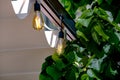 Textile awning in the backyard gazebo with a garland of strings of retro edison lamps. Royalty Free Stock Photo