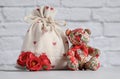 Textile bag with a gift. Red hearts are depicted on the fabric. A cute textile red bear and flowers are sitting nearby. White Royalty Free Stock Photo