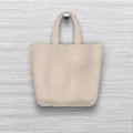 Textile textured biege tote bag hanging on the wooden textured wall. Realistic vector mockup for shopping design.