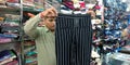 textiles shopkeeper showing latest outfit in black color at garment store