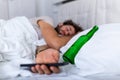 Texting while drunk concept. Young man lying in bed deadly drunken holding empty bottle of booze. intoxicated with alcohol . Royalty Free Stock Photo