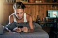 Texting is a part of his morning routine. a young man texting on his cellphone while lying in bed.