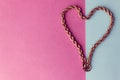 Texture of a beautiful golden festive chain unique weaving in the shape of a heart on a pink purple blue background and copy space Royalty Free Stock Photo