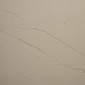 Texture of a beige, slightly rough wall featuring visible cracks. The surface displays Royalty Free Stock Photo
