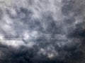 Texture of black tensioned high-voltage wires for electricity against a background of dark blue sullen storm sky with rain clouds Royalty Free Stock Photo