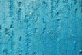 The texture of a blue-painted concrete wall with cracked and swollen paint