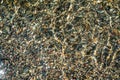 The texture of the bottom. Many small stones are visible under the clear water. Water ripples of the sea, sun rays on Royalty Free Stock Photo