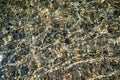 The texture of the bottom. Many small stones are visible under the clear water. Water ripples of the sea, sun rays on Royalty Free Stock Photo