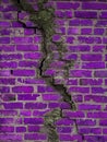 Texture of a brick wall with cracks in purple. Destroyed ancient wall violet. Brick background copy space